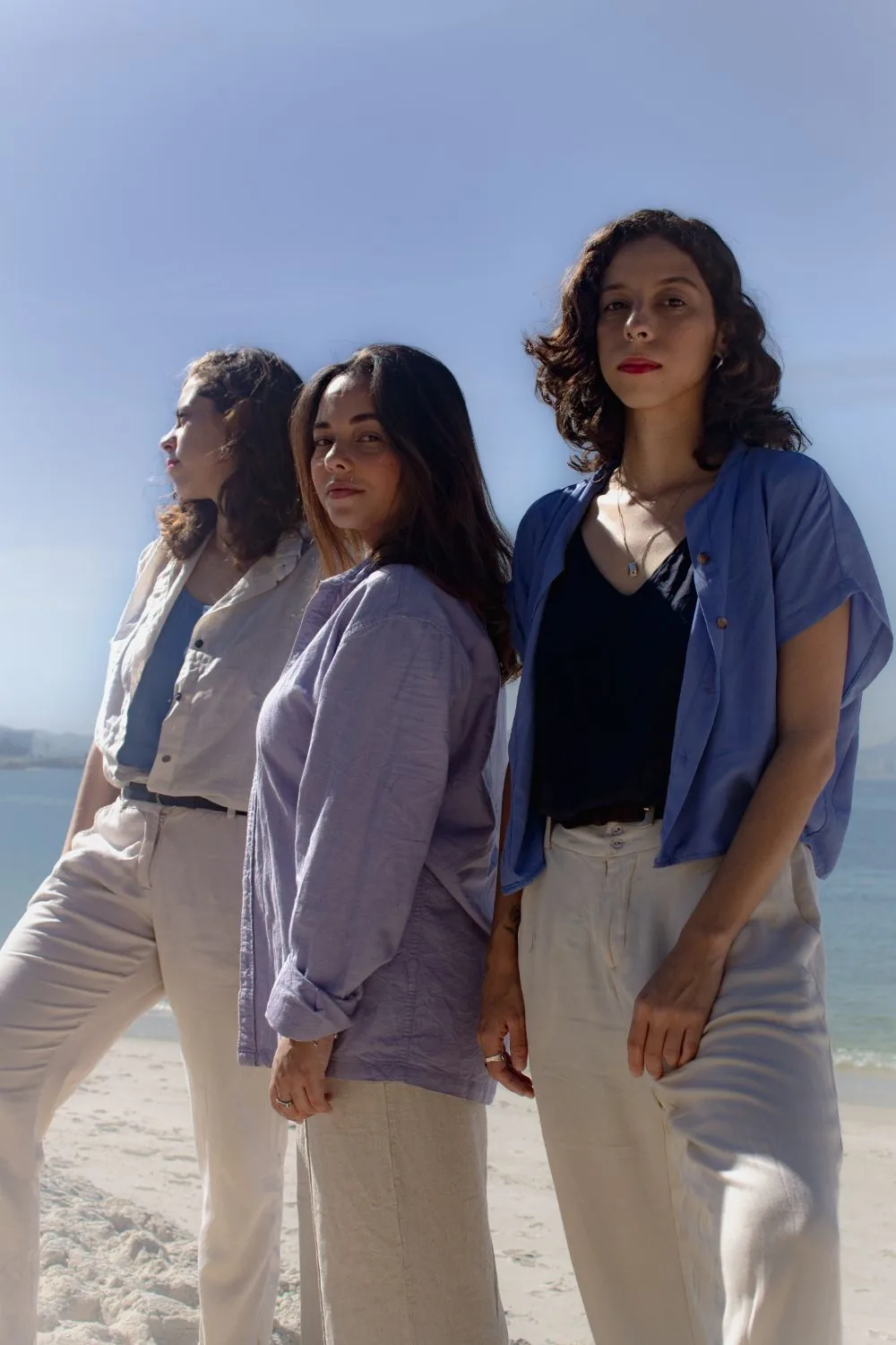 As três em pé na areia, mar atrás