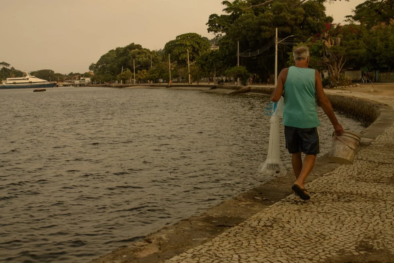 Pescador atravessando a orla com a rede
