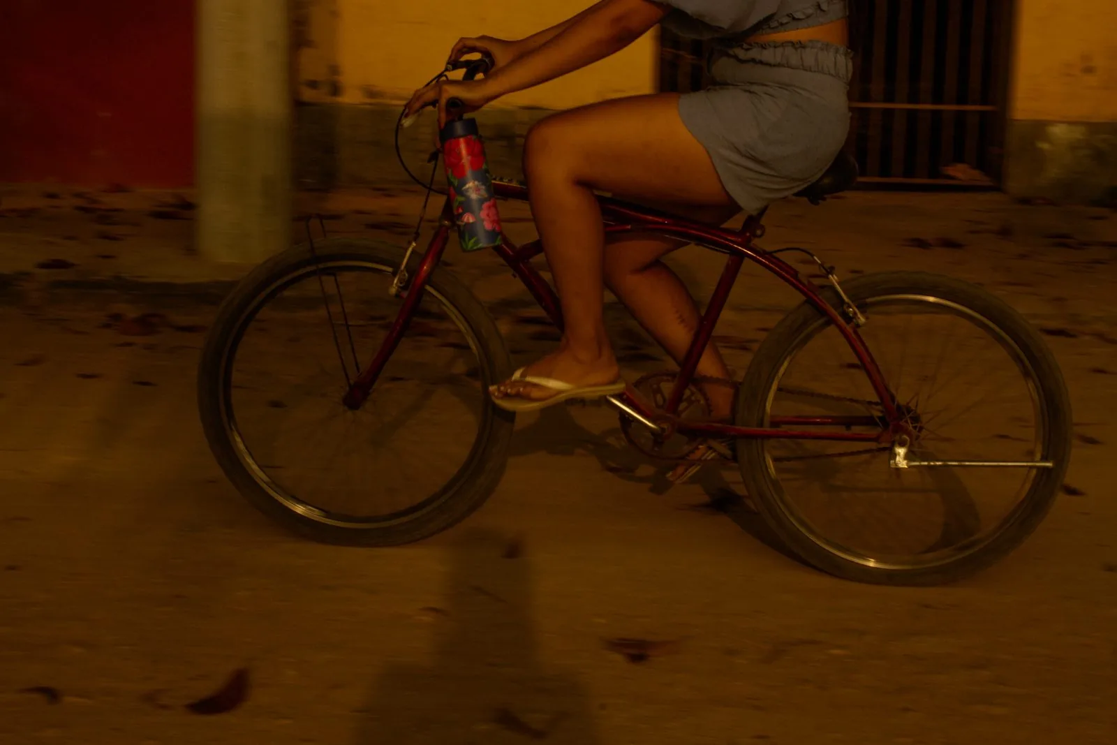 Ciclista de bermuda cinza passando, garrafa florida no quadro