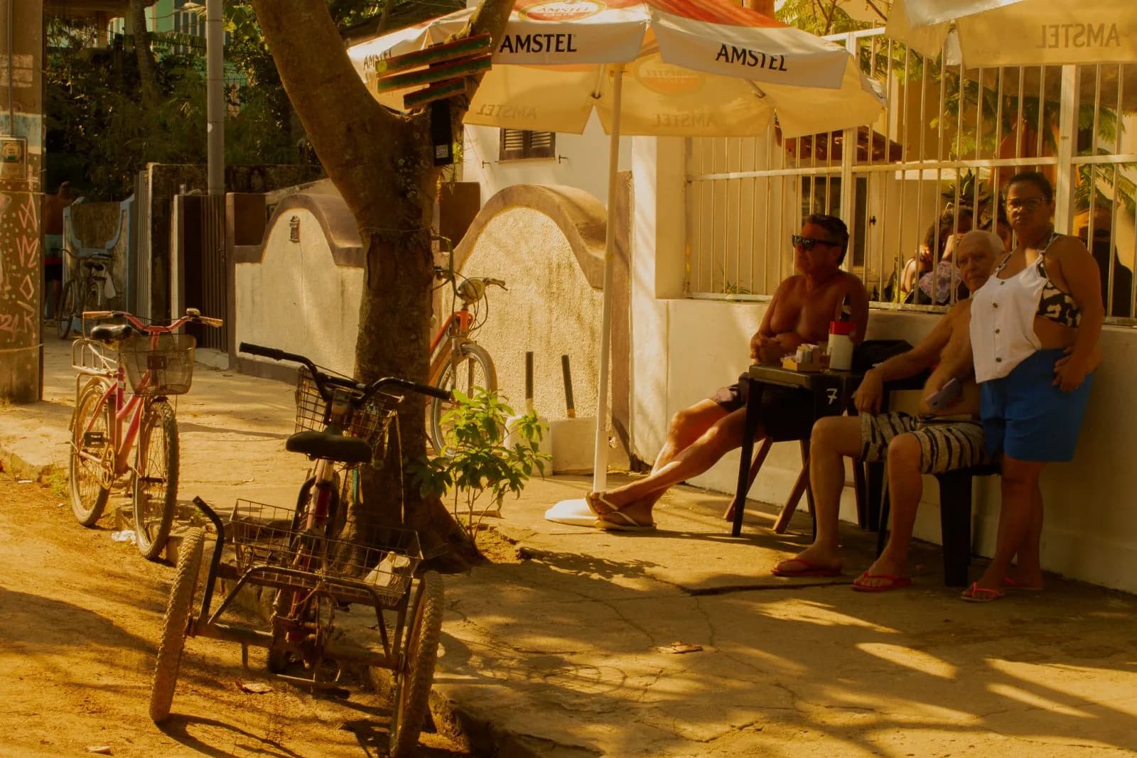 Mesas sob o guarda-sol e bicicletas encostadas
