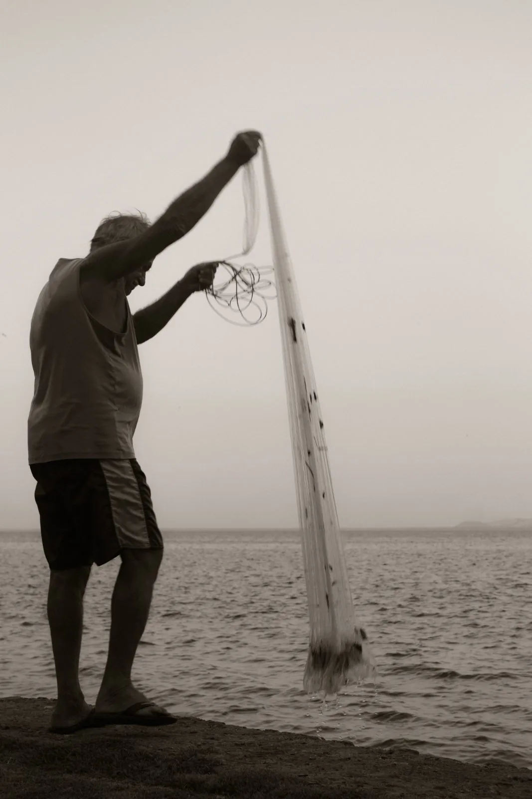 Pescador lançando a tarrafa contra o céu