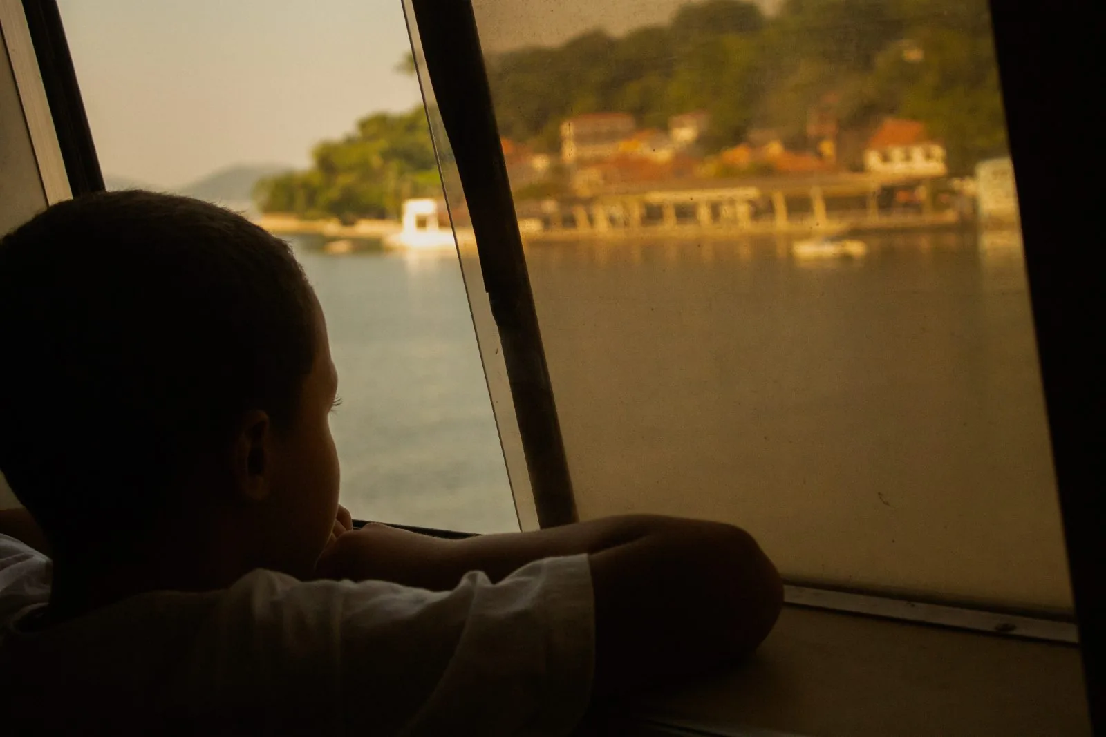 Menino apoiado na janela olhando a ilha