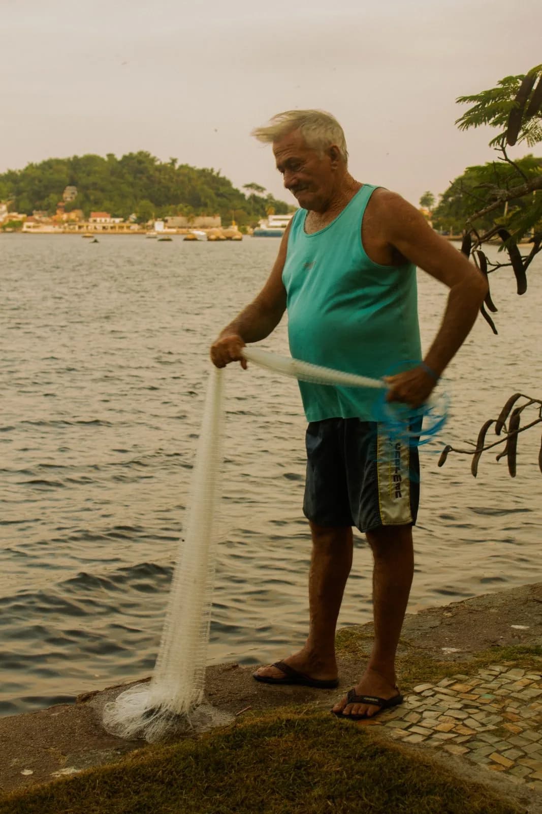 Pescador recolhendo a rede na beira