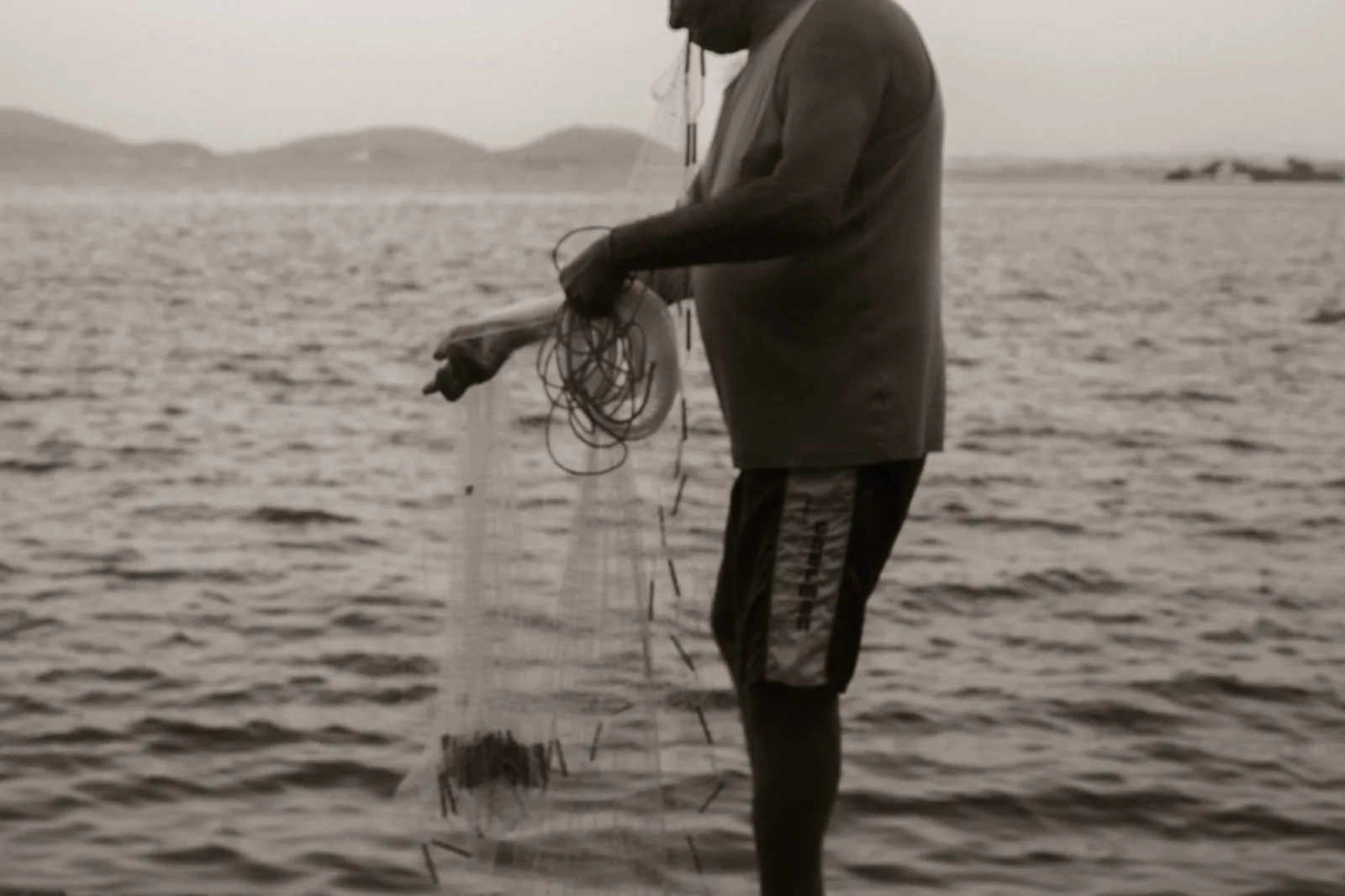 Pescador estendendo a rede, preto e branco
